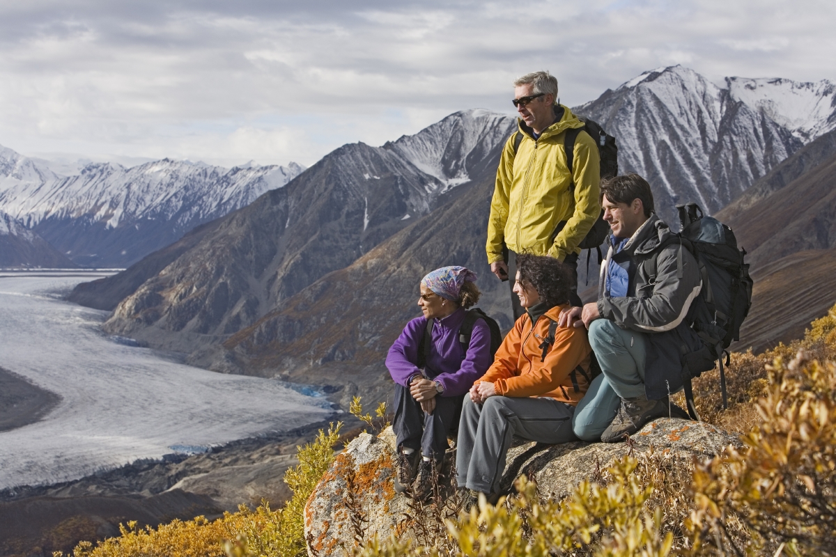 People sitting on the top of a mountain looking at a glacier